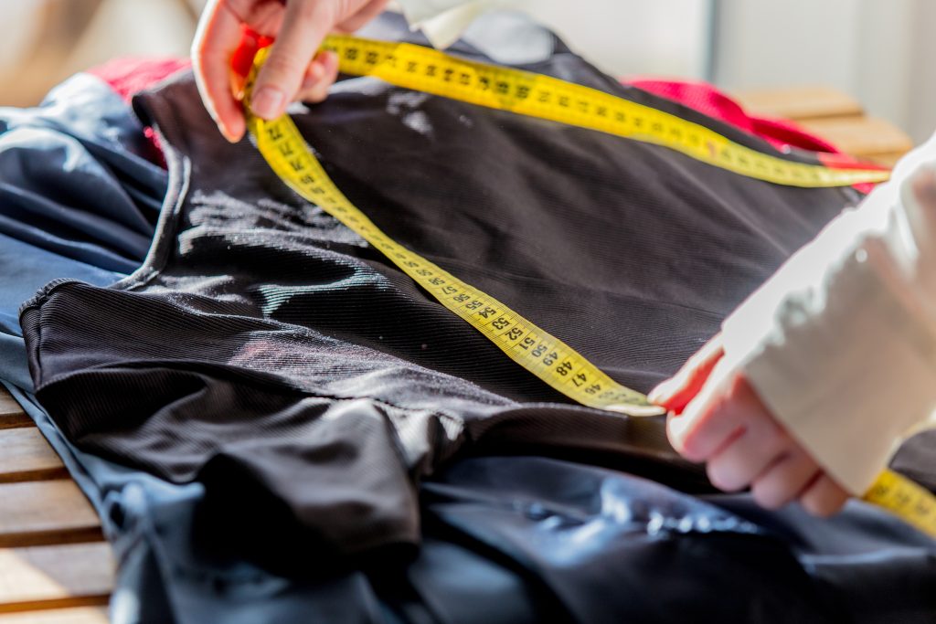 A quality control inspector checking the stitching and measurements of a finished garment against international AQL standards.